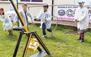 Kids in a mad science lab coat and safety goggles playing with catapult